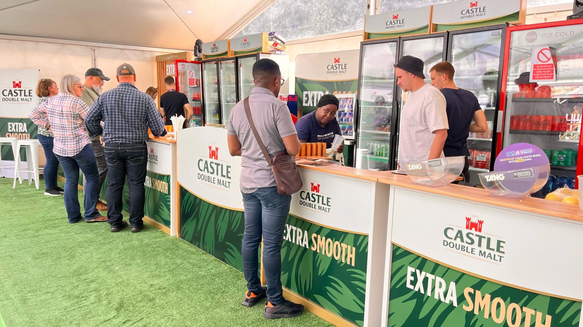 Castle Extra Smooth branded bar counter with staff serving guests