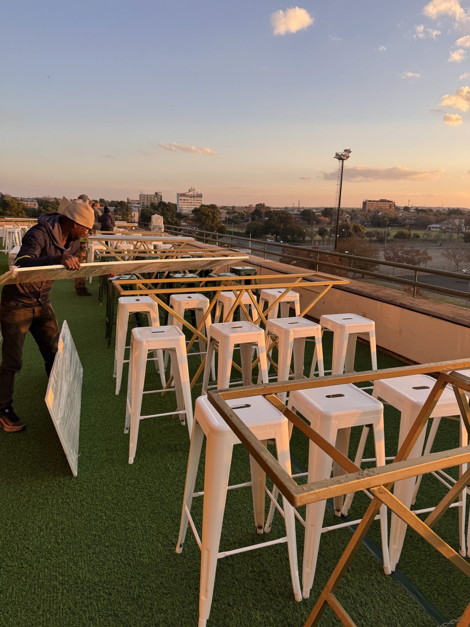 Golden hour over a stadium hospitality build with wooden high stools