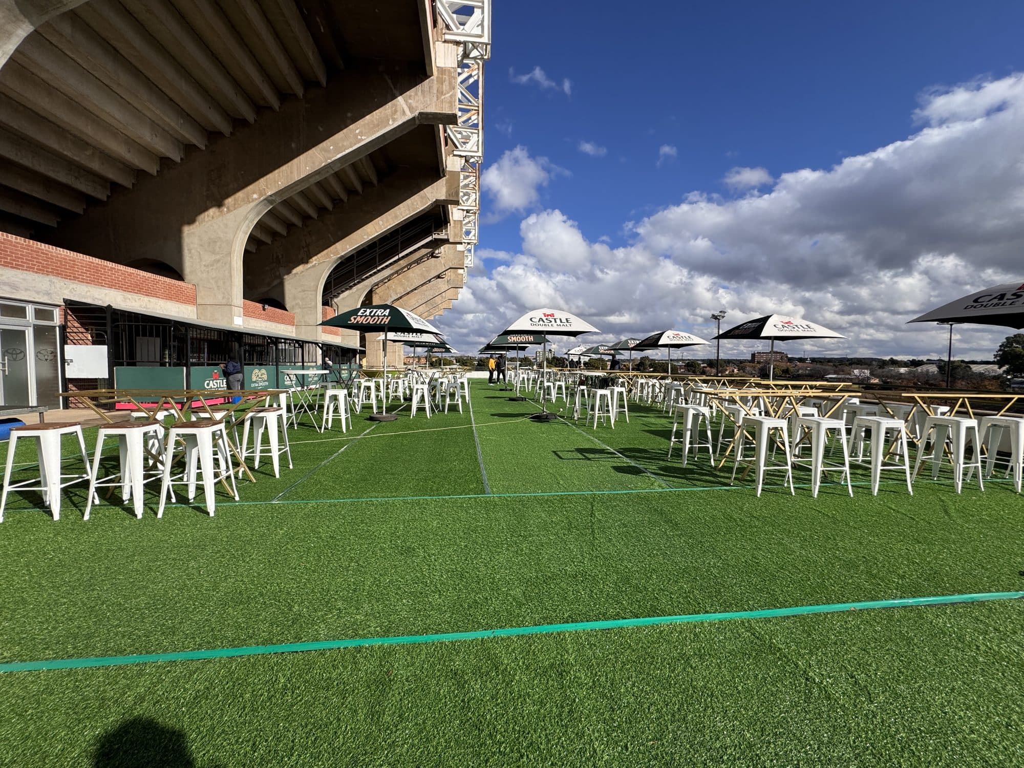 Castle Lager branded hospitality area with umbrellas and high tables at a stadium