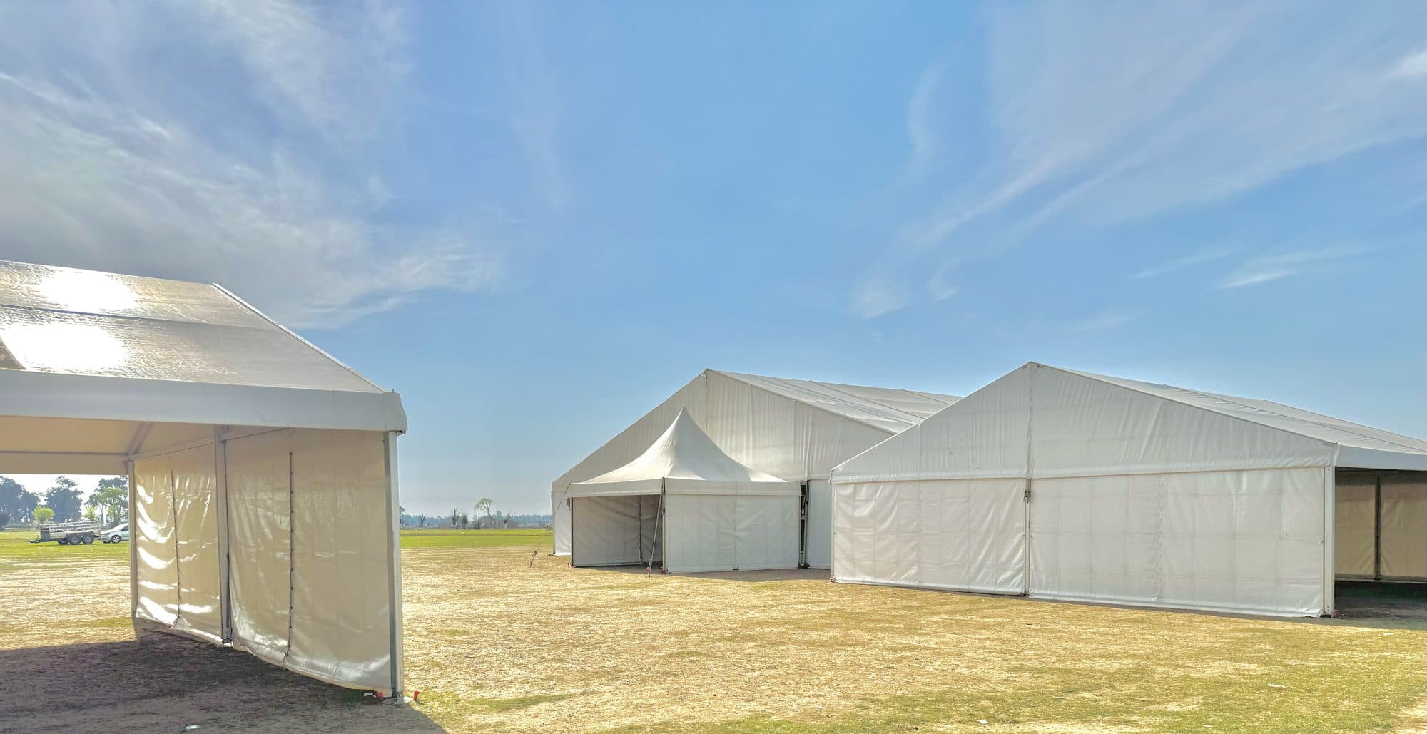 Large white frame marquee on an open field under a blue sky