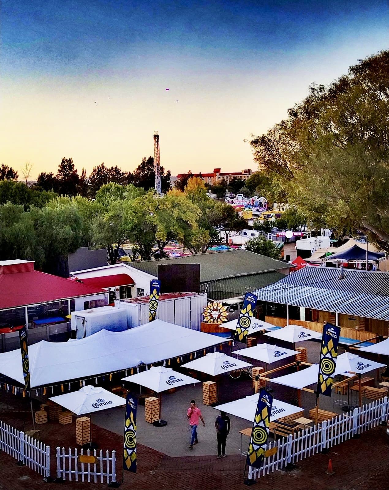 Festival grounds at dusk with branded gazebos and picket fencing