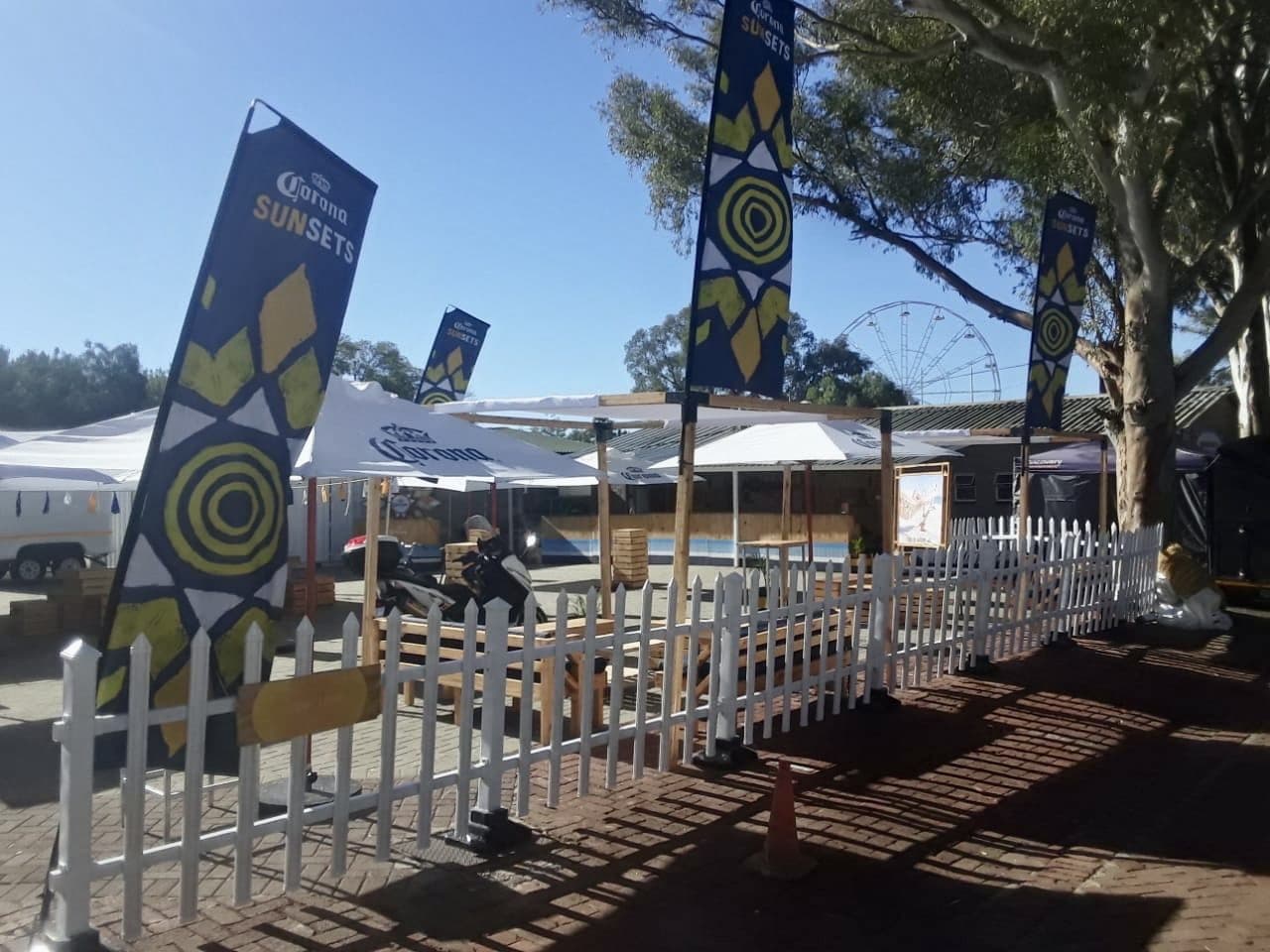 Festival site with branded totems, umbrellas and white picket fencing